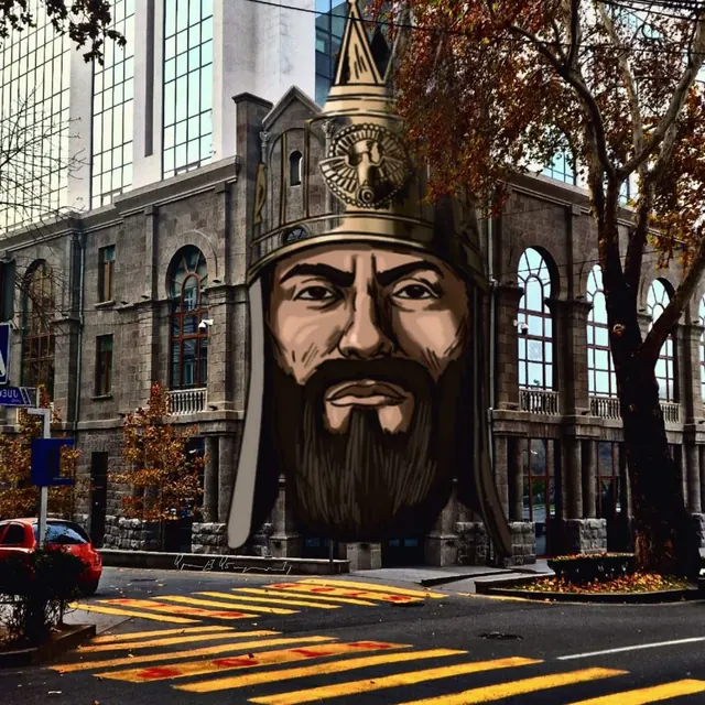 Голова воина в островерхом шлеме, вписанная в фасад каменного здания